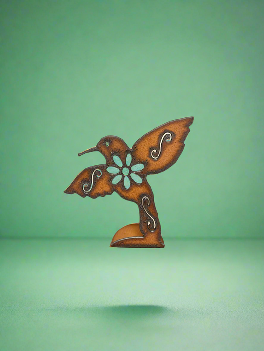 A rustic metal standing figurine of a hummingbird with a flower, with a brown patina finish.